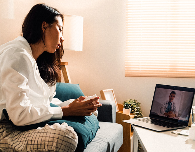 Image of a woman sitting on a couch using a laptop for virtual care.