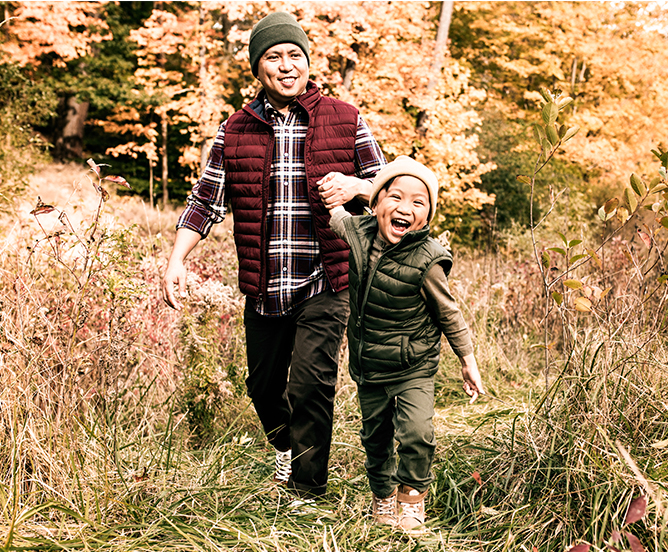 Father and kid on a forest walk, holding hands and laughing.