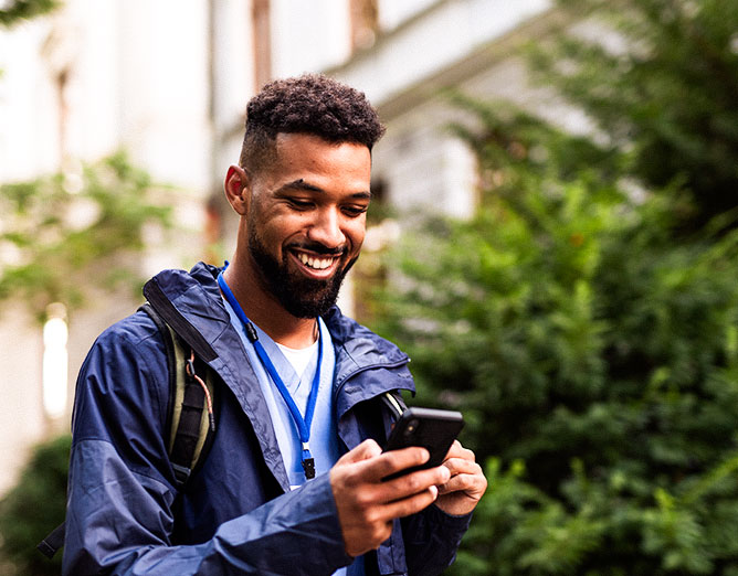 Young black man viewing content on mobile phone in outdoor setting