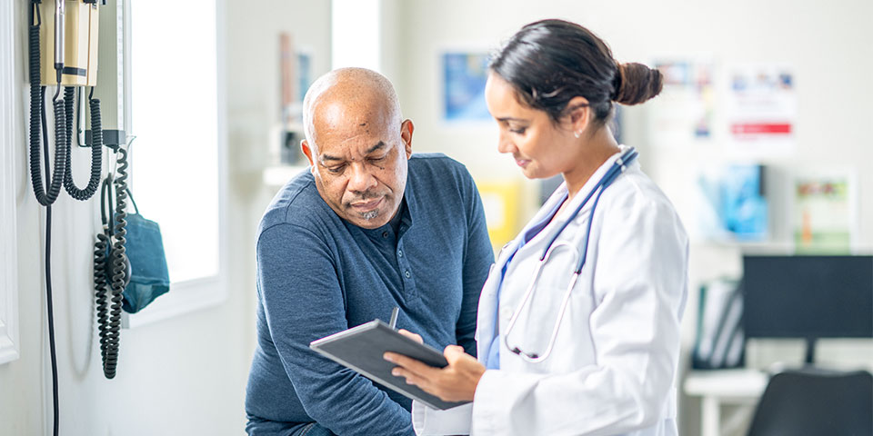 Female healthcare provider viewing information on a tablet with male patient